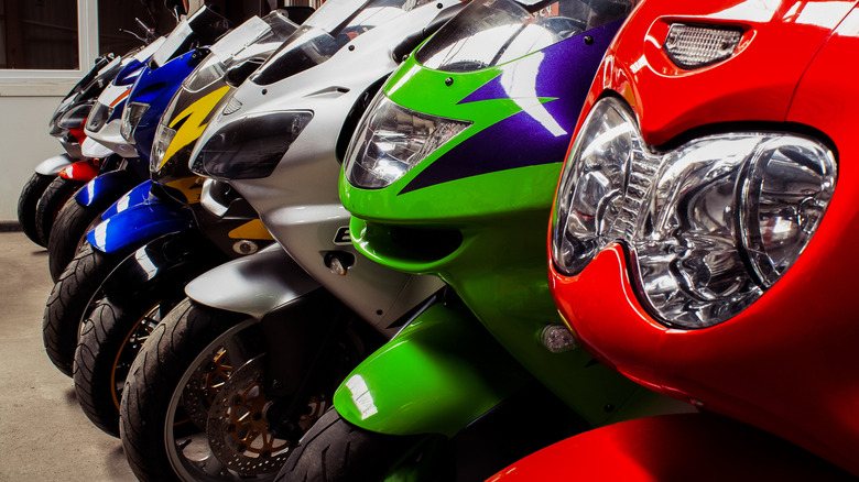 A colorful array of sportbikes are lined up indoors.