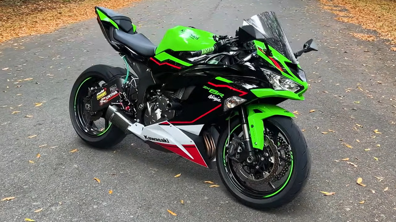 A Kawasaki Ninja ZX-6R with green and red bits sits on an empty street in autumn.