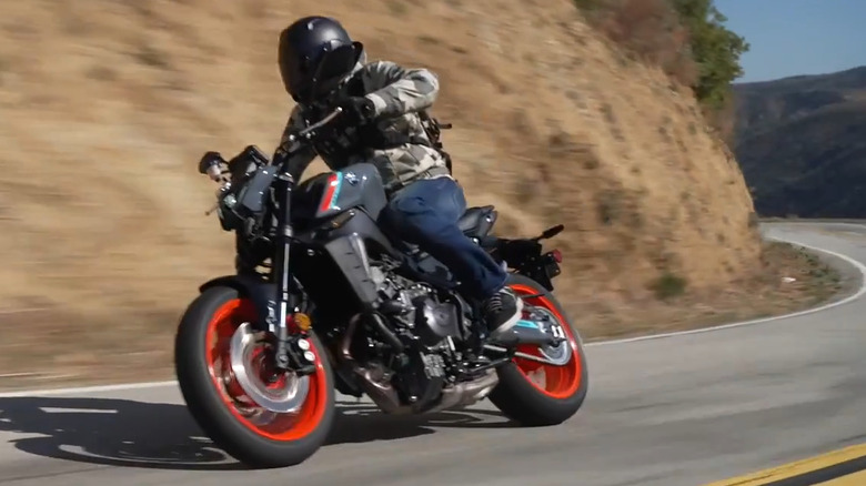 A man rides a Yamaha MT-09 around a bend through mountains.