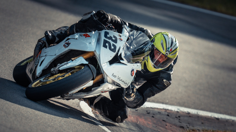 A motorcyclist leans hard as he corners on a sharp bend.