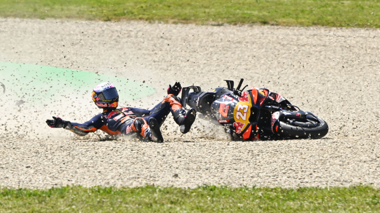 A motorcycle rider in racing gear skids along the ground during a wreck.