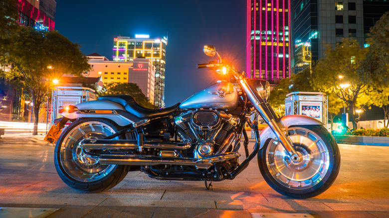 Harley-Davidson Fat Boy motorcycle parked at night on a lit city sidewalk.