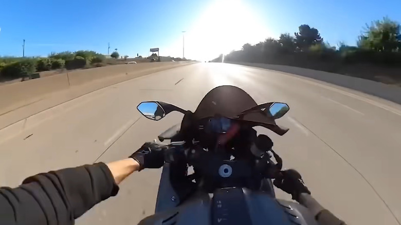 A rider's point of view is shown as they struggle to control the handlebars on an open highway.