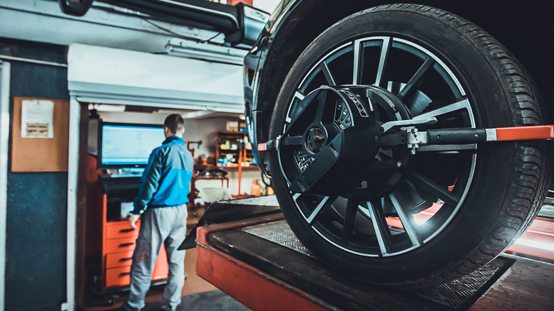A mechanic works on a wheel alignment in a shop.