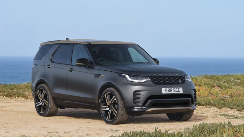 A gray Land Rover Discovery Tempest Edition SUV in a right front three-quarter view parked overlooking the ocean
