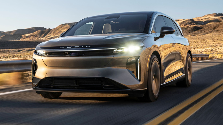 A gold Lucid Gravity Touring SUV in a front left view driving on a two-lane desert mountain road