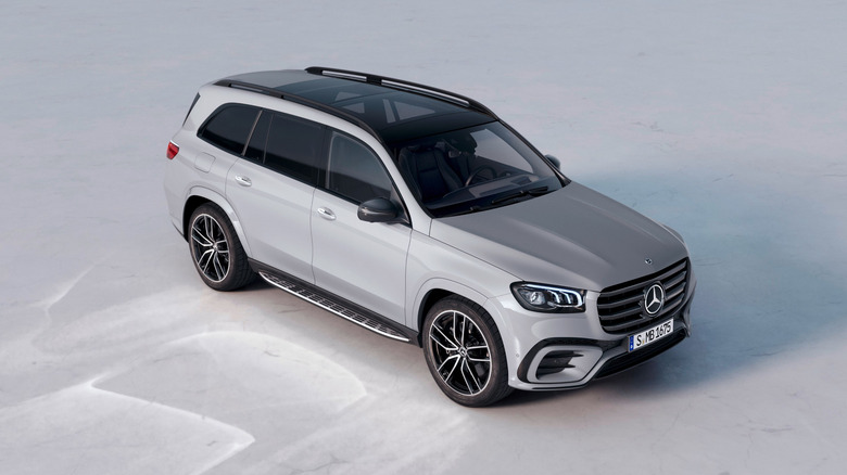 A light gray 2024 current-gen Mercedes-Benz GLS SUV in a high right front three-quarter view parked on a plain gray surface