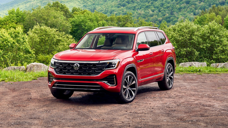 A red current-gen 2024 Volkswagen Atlas SUV in a left front three-quarter view parked by a mountain overlook
