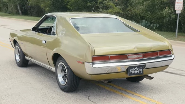 A rear 3/4 shot of a 1970 AMC AMX parked in the middle of the road
