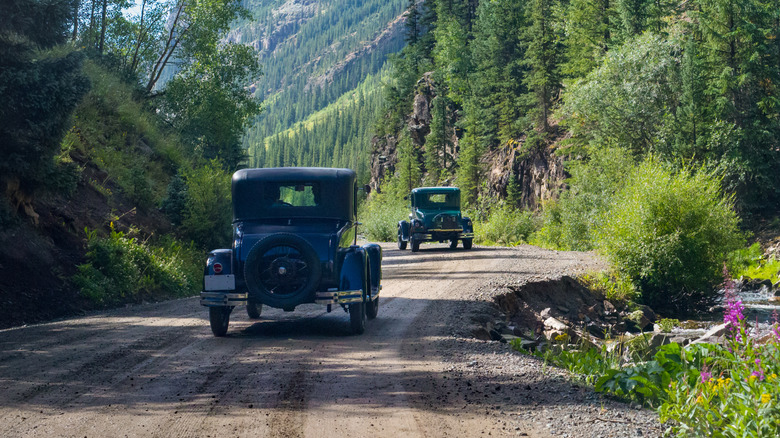 Vintage cars driving along a dirt road