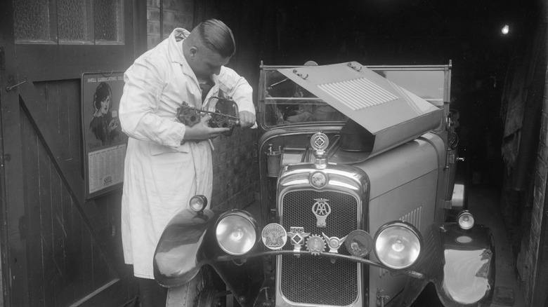 A male mechanic working on a 1920s Triumph engine