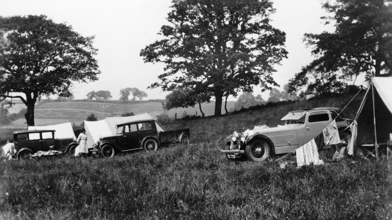 A black and white photograph showing a 1930s camping scene with vintage cars