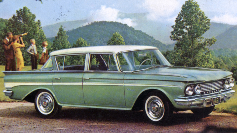 An old advertisement picture of a 1961 Rambler American parked outdoors with a family of four in the background.
