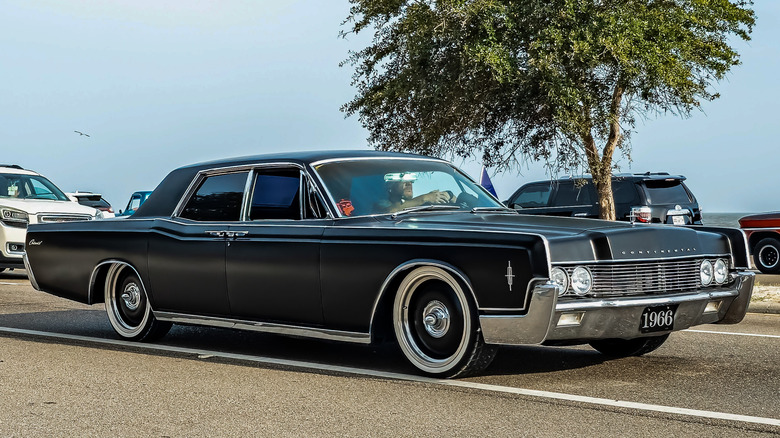 A 1966 Lincoln Continental in matte black on the road.