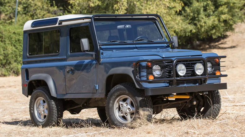 A front 3/4 view of Kim Basinger's 1997 Land Rover Defender 90 NAS parked off road.