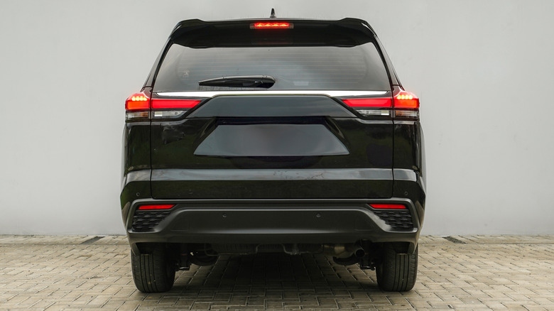 A rear view of a black MPV with deleted badges