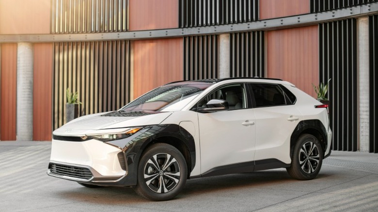 A white and black 2023 Toyota bZ4X parked in front of a modern architecture wall