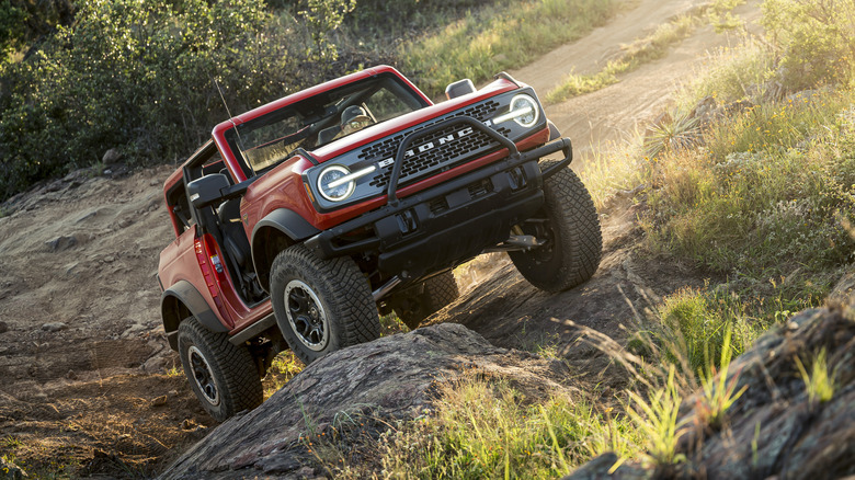 A red 2021 Ford Bronco driving up rocks and a hill.