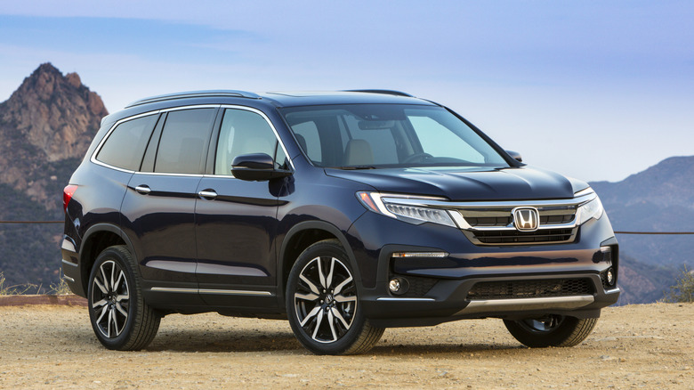 A blue 2021 Honda Pilot in front of mountains.
