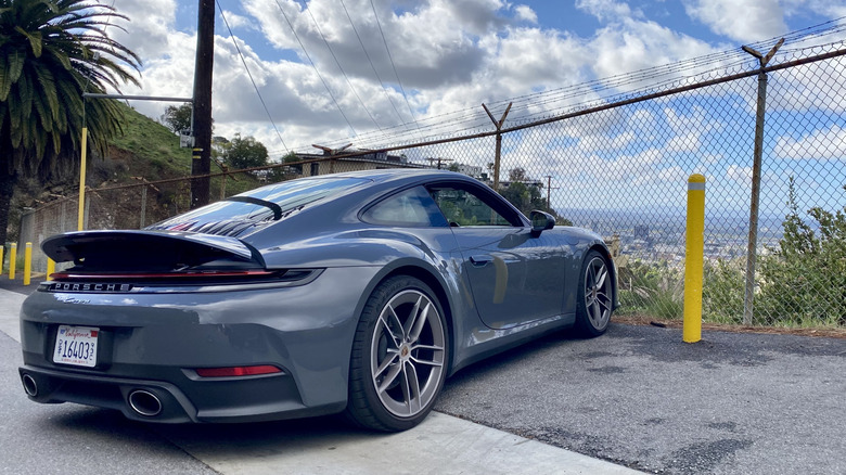 rear three quarters shot of the gray 911 parked in front of a fence