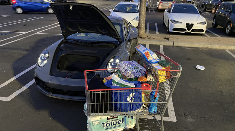 a full Costco shopping cart in front of the 911 with its hood open