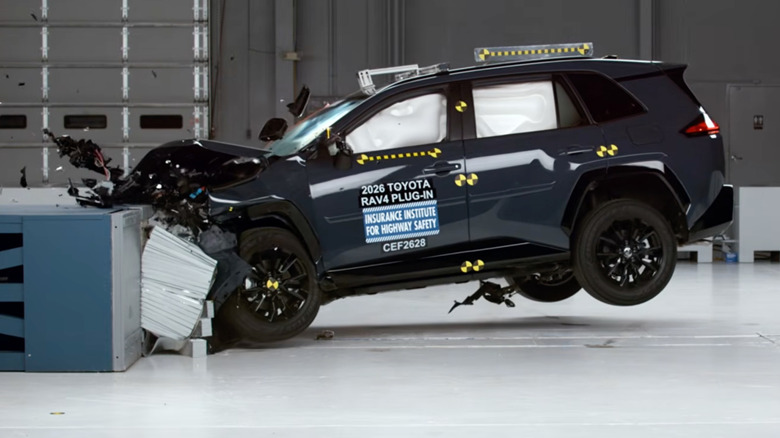 Side view of a dark gray RAV4 PHEV the moment it hits the barrier in the IIHS updated moderate overlap crash test