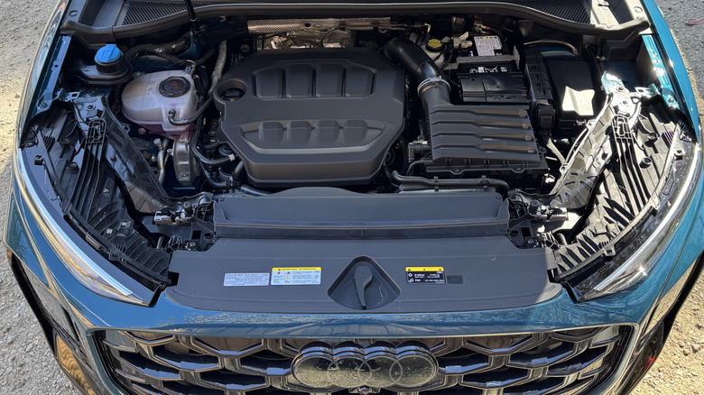 An under-hood shot of the blue Q3 showing its turbocharged 2.0-liter four-cylinder while parked on dirt