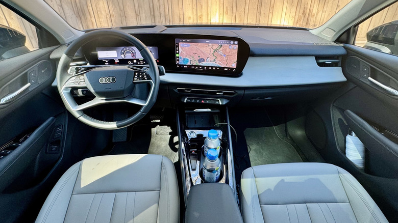 a wide shot of the Q3's new dashboard showing the map on the infotainment screen and a wooden fence out the windshield