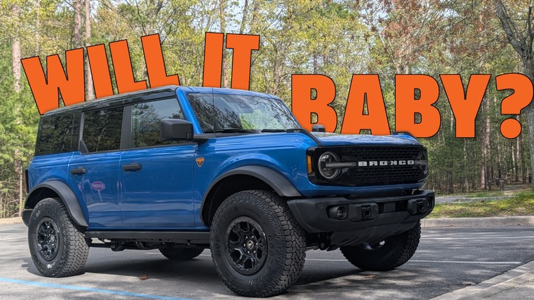 A blue Ford Bronco parked in front of some trees with the text Will It Baby in the background