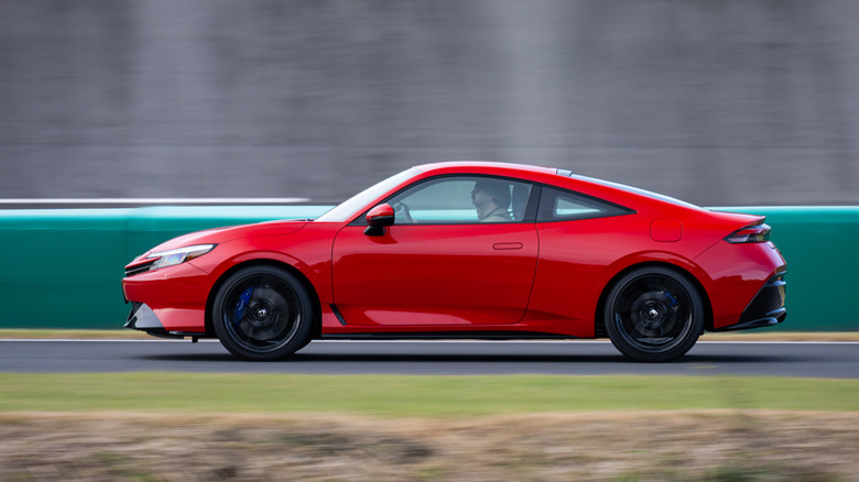 Side view of a red 2026 Honda Prelude  driving on track