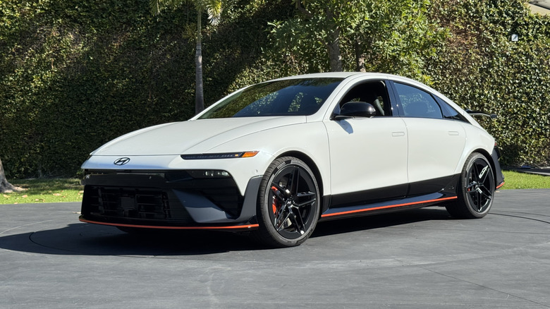 Front three-quarters shot of the white Ioniq 6 N parked on asphalt in front of a hedge