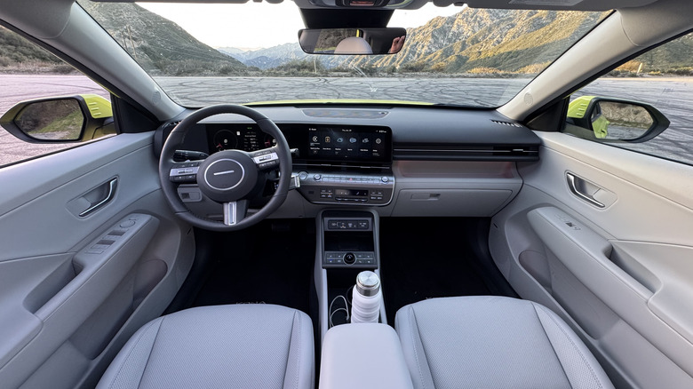 A side view of the blue Q3 parked on dirt in front of a grassy hill and a blue sky