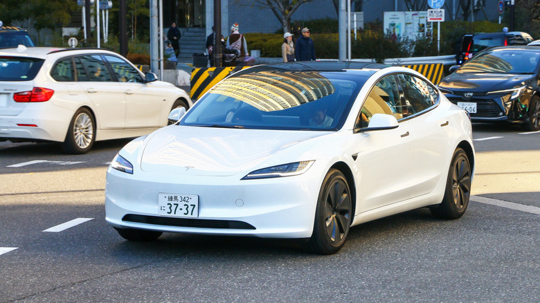 White battery electric car Tesla Model 3 in the city street.
