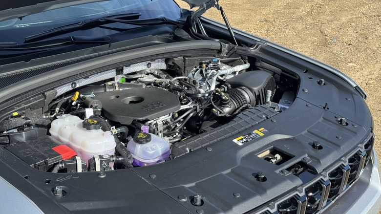 A photo looking under the hood of the Grand Cherokee parked on dirt showing the new turbocharged engine
