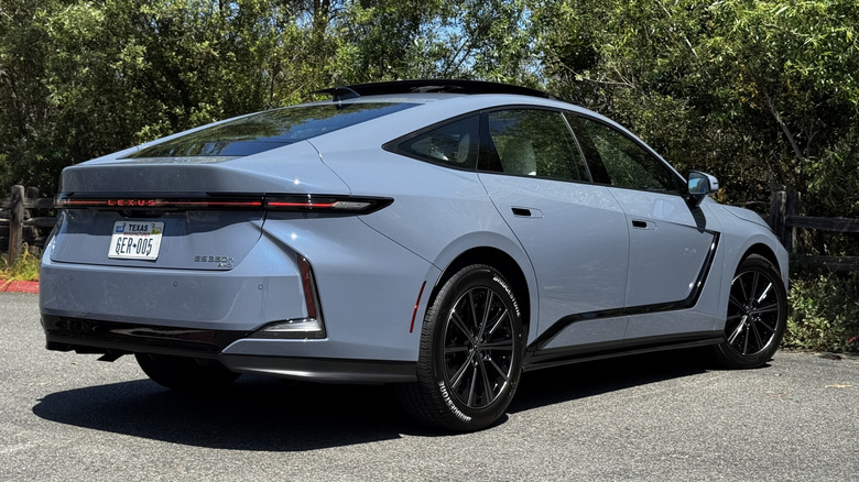 A rear three-quarters shot of the Wavelength colored ES350h parked on asphalt in front of bushes