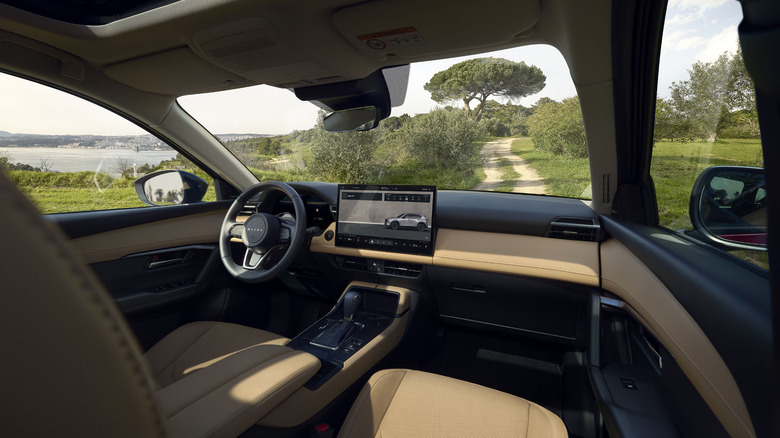 A look at the dashboard of the new CX-5 with a tan leather interior parked on a dirt road with trees grass and a lake out the windows