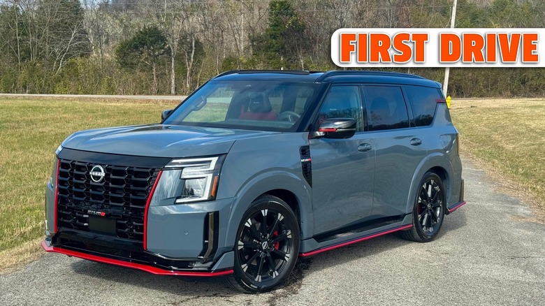 A front three quarters shot of the gray Nissan Armada Nismo parked on asphalt next to grass in front of trees