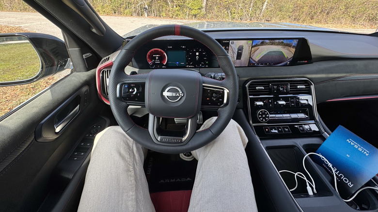 A photo of the driver's POV with trees out the windshield and the surround view camera on the infotainment