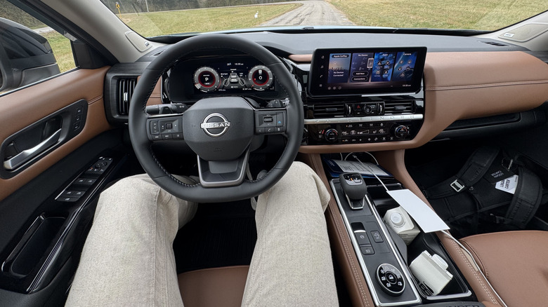 The driver's POV looking at the brown leather inside a Pathfinder Platinum with digital gauges and a HUD