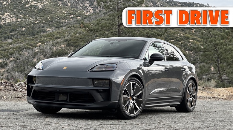 Front three quarters shot of a Slate Grey Neo Macan GTS Electric parked on cracked asphalt in front of shrub-covered mountains