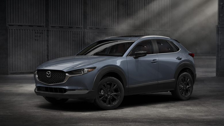 A gray Mazda CX-30 parked in front of some moody shipping containers.