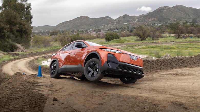 An orange Subaru Uncharted cresting a muddy hill