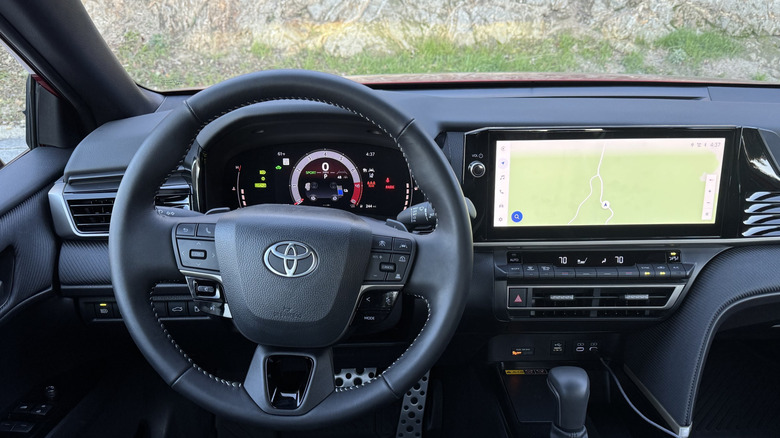 A close-up of the driver's POV in the Camry showing the steering wheel and infotainment screen
