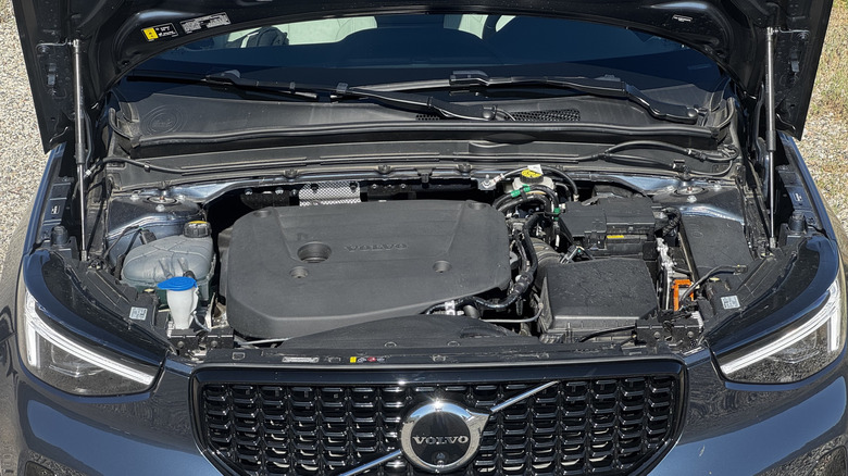 An underhood shot of the blue XC40 parked on gravel with the DRLs on