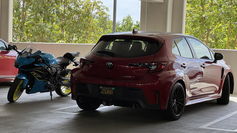 A blue, purple, and yellow Yamaha R7 in a dark garage next to a GR Corolla