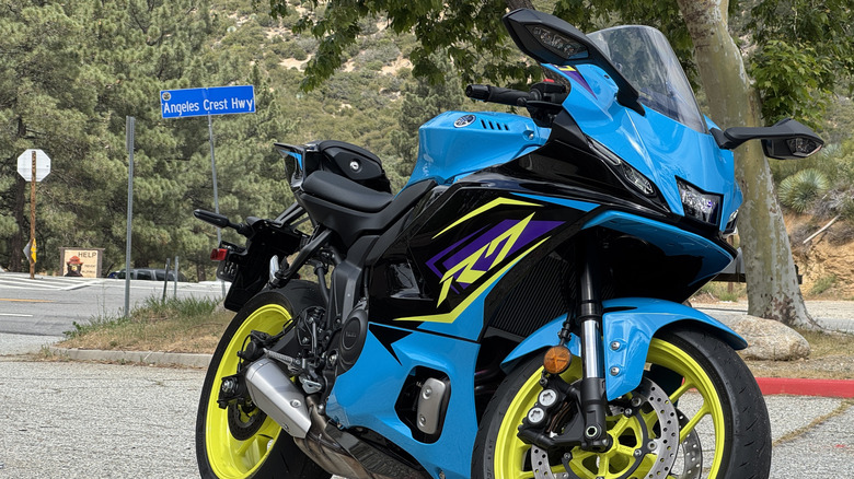 A blue, purple, and yellow Yamaha R7 in front of a street sign for Angeles Crest