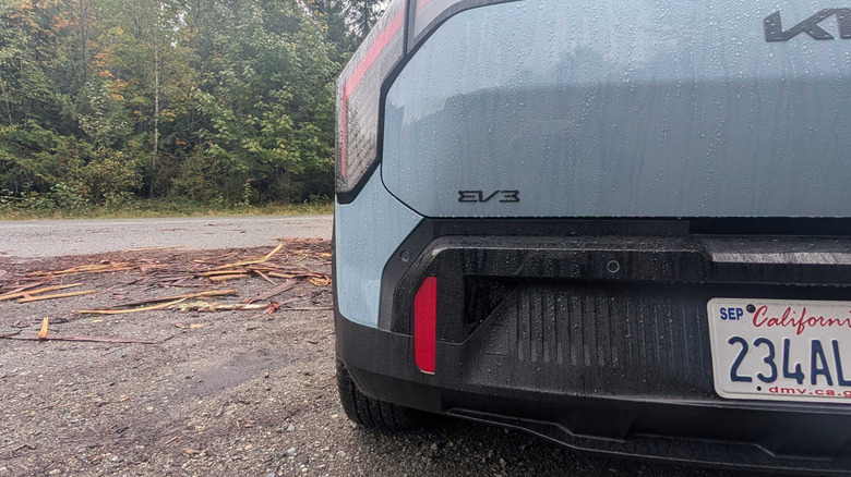 The rear of a 2027 Kia EV3 parked in front of trees