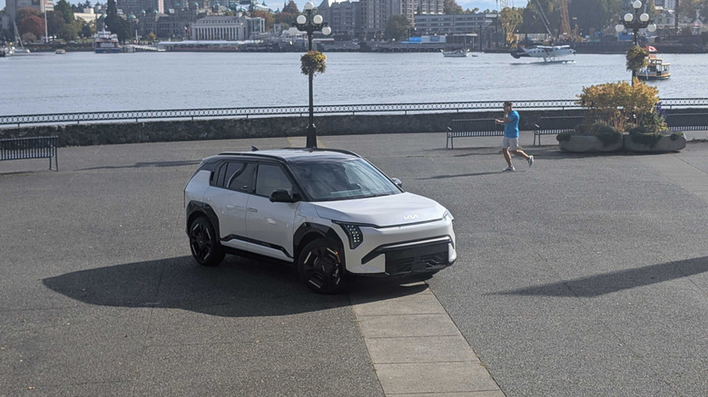 A white 2027 Kia EV3 parked in front of a river