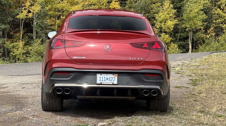 Rear shot of the red GLE53 coupe parked on gravel in front of yellow-and-green trees