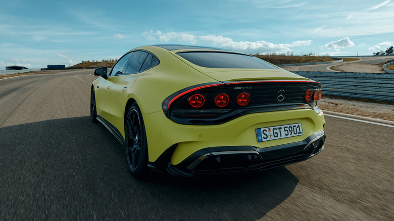Rear 3/4 view of a yellow 2027 Mercedes-AMG GT 4-Door Coupe EV driving on track
